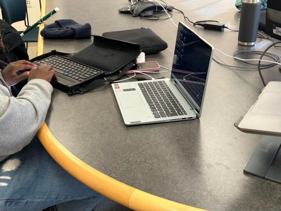 A research session in progress: a participant’s hands on a braille display keyboard beside a laptop on a table