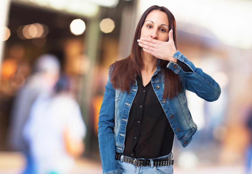 A woman on a busy street holds her hand over her mouth
