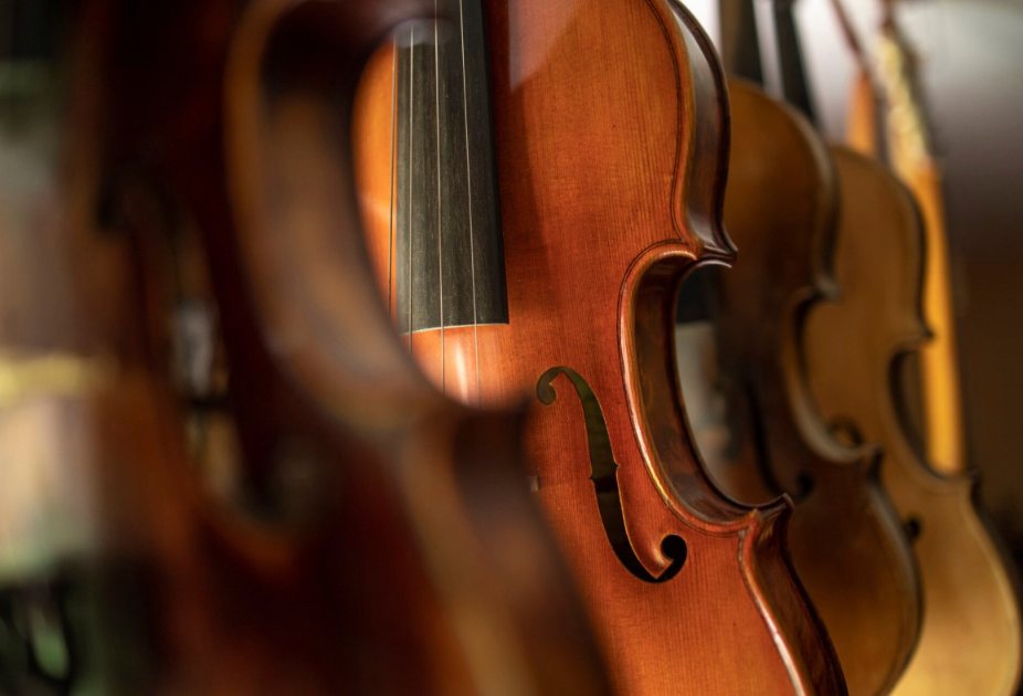 Violins hanging in a row in a workshop, one in sharp focus